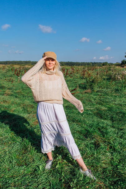 Happy beautiful blond woman walking in a green field - Foto, afbeelding