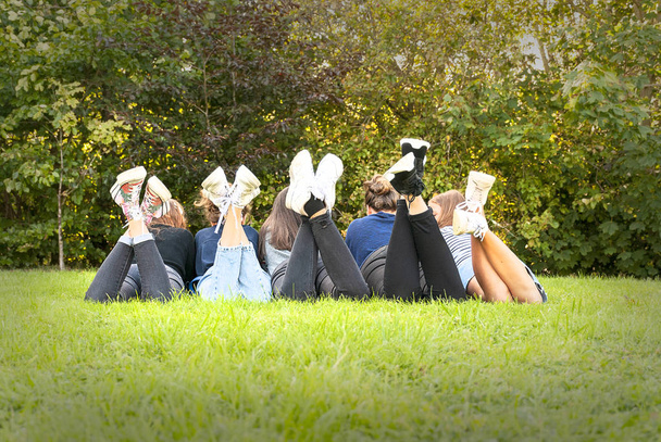 Imagem de pernas e sapatos de jovens adolescentes meninas em pé na grama de um parque. Desfrutando de um momento feliz e um lugar perfeito. Divertindo-se e desfrutando de sua amizade. Conceito de unidade e diversidade
. - Foto, Imagem