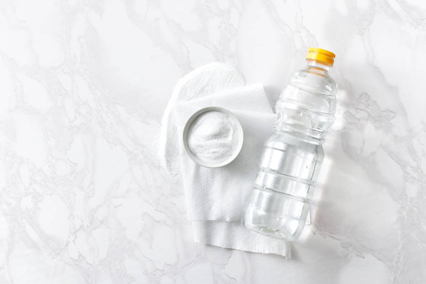 Vinegar in a bottle, baking soda and a cleaning cloth on a marble surface - Photo, Image