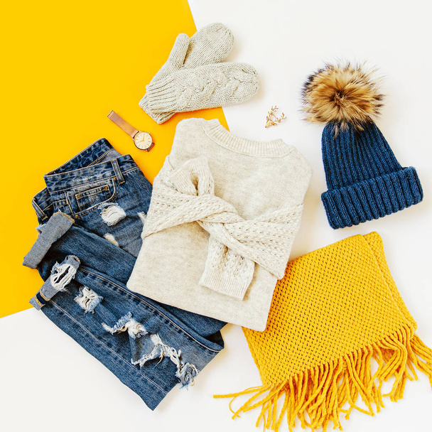 Blue winter hat with jeans, sweater, mittens and yellow scarf on white background. Women's stylish autumn or winter outfit. Trendy clothes collage. Flat lay, top view. - Fotografie, Obrázek