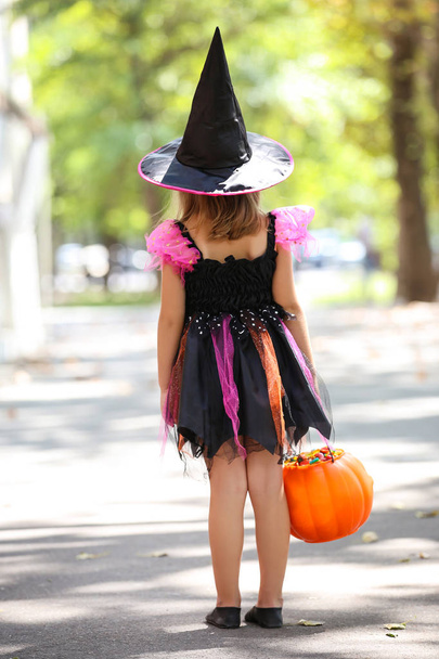 Young girl in halloween costume with pumpkin bucket - Фото, изображение