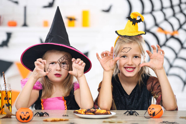 Young girls in halloween costumes sitting by the table - Фото, зображення