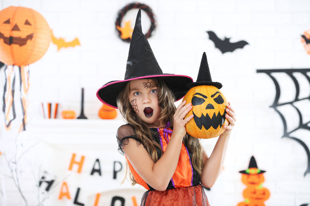 Beautiful girl in halloween costume holding pumpkin with hat - Foto, imagen