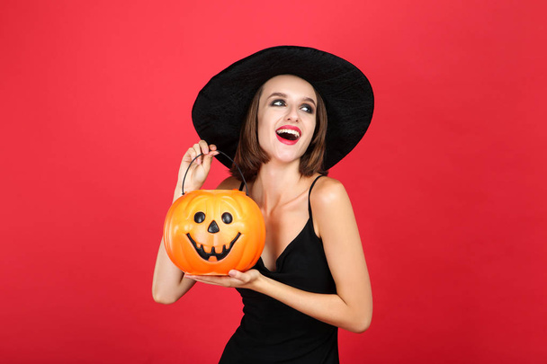 Happy young woman in black halloween costume holding pumpkin buc - Valokuva, kuva