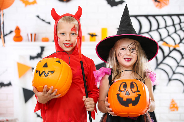 Chica joven y niño en trajes de halloween con cubos de calabaza
 - Foto, imagen