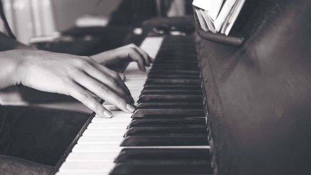 Greyscale shot of a female playing the piano - Фото, зображення