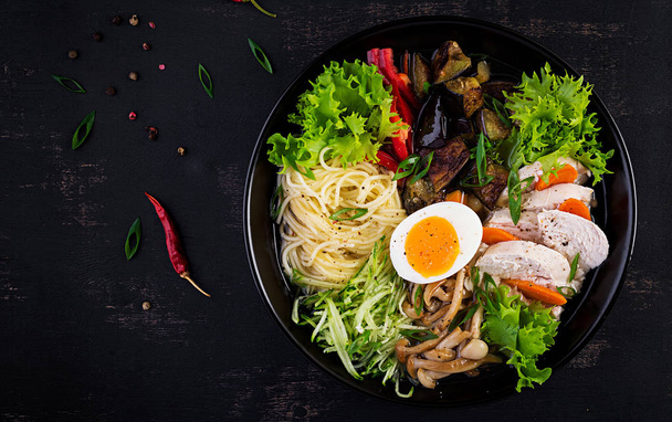 Japanese ramen soup with chicken, egg, shimeji mushrooms and eggplants on dark wooden background. Chanko nabe, sumo soup. Top view - Photo, Image