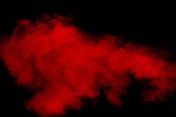 Nuage d'explosion de poudre rouge sur fond noir. Mouvement de gel des particules de poussière de couleur rouge éclaboussures. - Photo, image