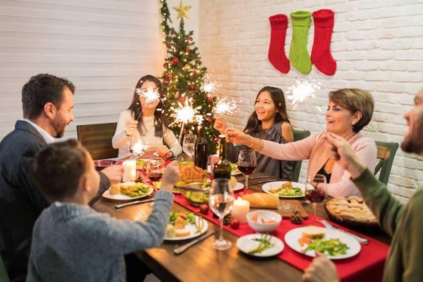 Szczęśliwa rodzina ciesząca się świąteczną kolacją z ogniem w domu - Zdjęcie, obraz