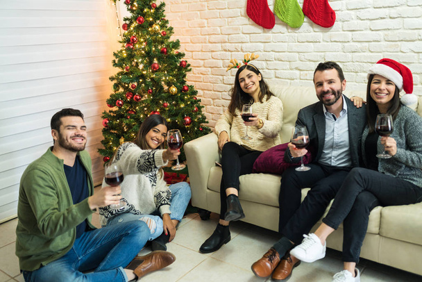 幸せな男性と女性の友人とともに赤ワイントースト楽しむクリスマスで自宅 - 写真・画像