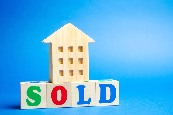 Wooden blocks with the word Sold and wooden miniature house. The concept of the sell of real estate, apartments and residential premises. Rent and mortgage. Market analysis - Foto, Imagem