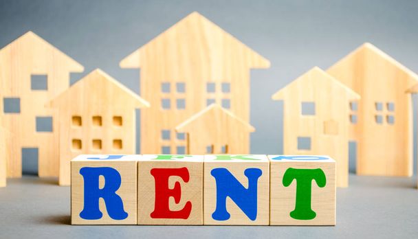 Wooden blocks with the word Rent and wooden houses. The concept of renting housing and real estate. The cost of a rented home or apartment. Rental. - 写真・画像
