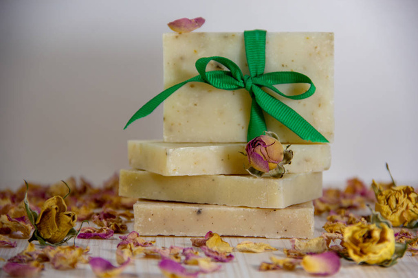 Natuurlijke handgemaakte zeep versierd met een groen lint met een strik, gedroogde rozenknoppen, rozenblaadjes. Spa biologische zeep. - Foto, afbeelding