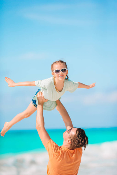 ビーチ休暇中に楽しい時間を過ごしている女の子と幸せなお父さん - 写真・画像
