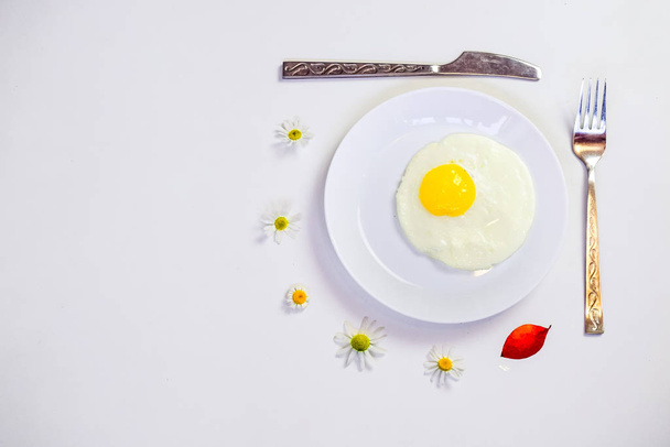 scrambled eggs on a white plate and a bright white table with additions  - Фото, изображение