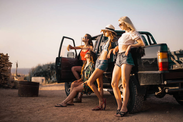 A group of girls leaning against a car - 写真・画像