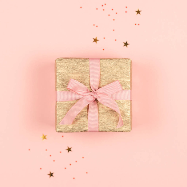 Golden gift box with pink bow on the pink background with sparkles.  - Foto, Imagem