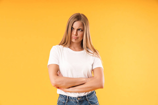 Image of uptight offended woman wearing casual t-shirt frowning and standing with arms crossed - Фото, изображение