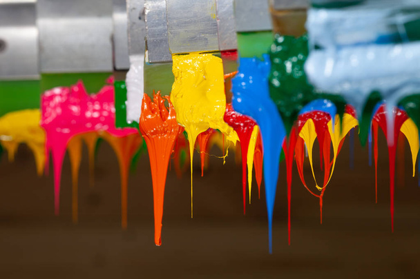 varios colores de goteo tinta en impresoras mango en la fábrica de camisetas cuelgan en el almacenamiento
 - Foto, imagen