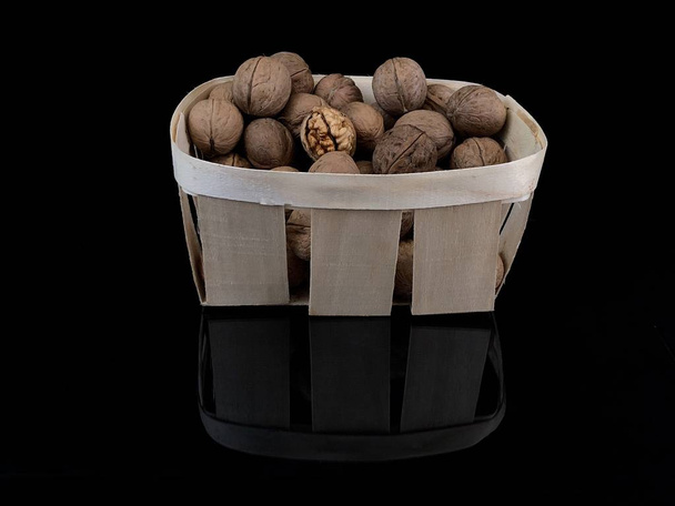 Inshell walnuts on a black background. Ripe walnut in a hard shell. - Photo, Image