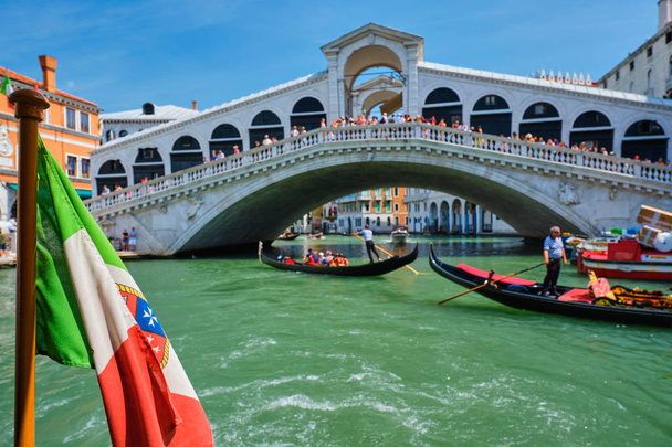 Italian maritime flag with Rialto bridge with gondolas in the bacground. Grand Canal, Venice, Italy - Photo, Image