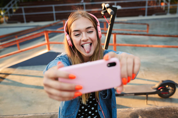 Happy positive young teenage girl holding mobile phone take a selfie. - Foto, Imagem