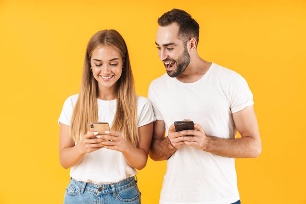 Image of cheerful man smiling while looking at cellphone of his girlfriend - Foto, Bild