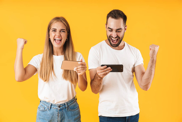 Image of ecstatic couple playing video games on smartphones together - Foto, afbeelding