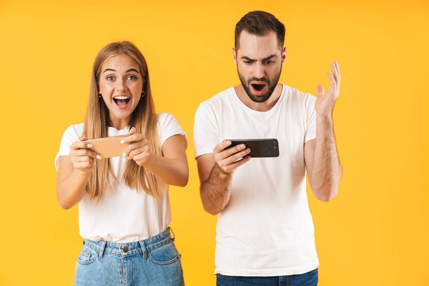 Image of emotional couple playing video games on smartphones together - Foto, immagini