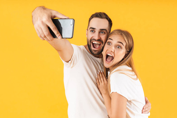 Image of young couple smiling while taking selfie photo on cellphone - Zdjęcie, obraz