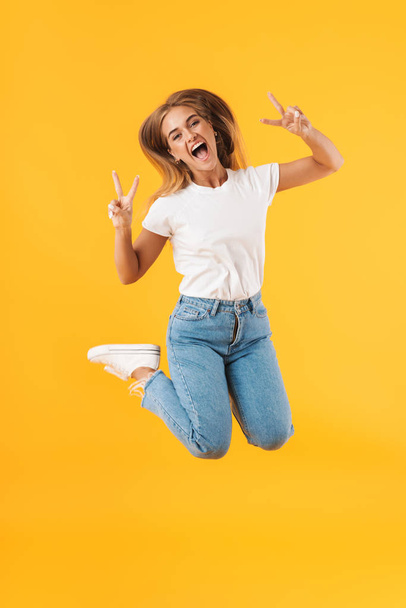 Full length image of delighted woman jumping and showing peace s - Фото, изображение