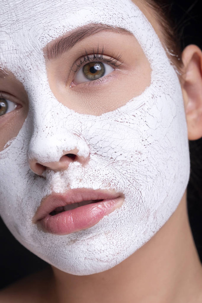 Krásná mladá Evropanka si nasadí na obličej hliněnou masku. beau - Fotografie, Obrázek