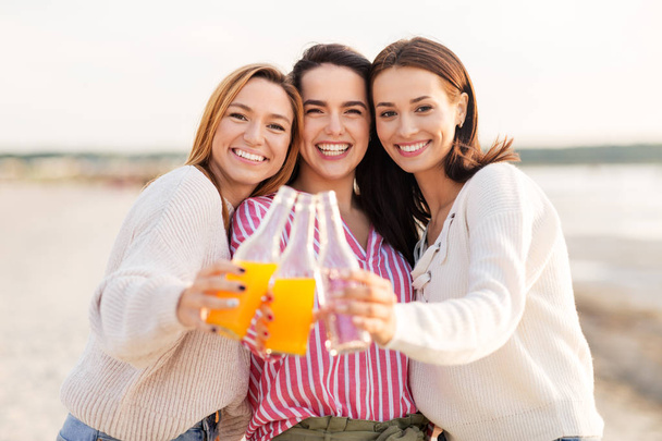 junge Frauen prosten sich am Strand alkoholfreie Getränke zu - Foto, Bild