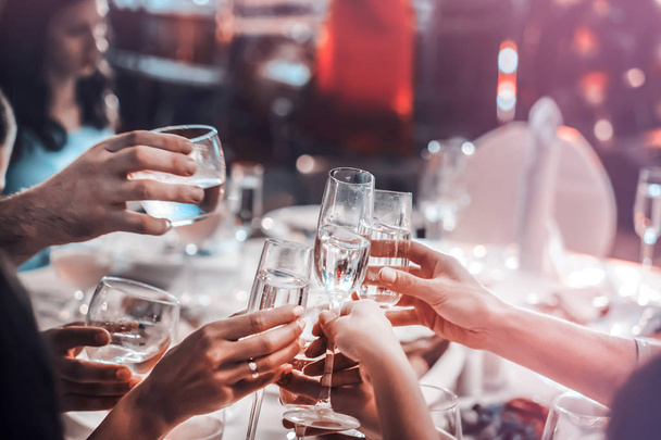 People hold in hands glasses with white wine. wedding party. friends toasting with a champagne above white table - Foto, Imagen