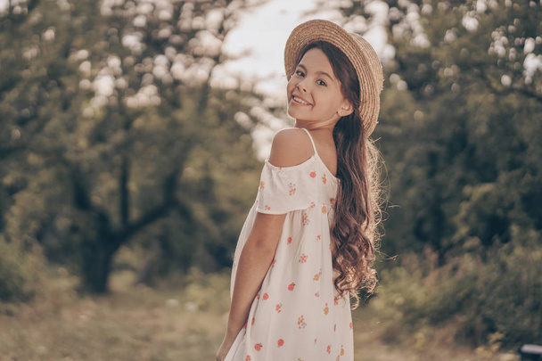Retrato de menina sorridente e feliz no parque no pôr do sol. Modelo de criança moderna alegre posando no jardim no verão
 - Foto, Imagem