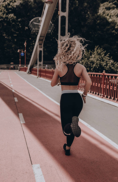 Young woman runner. Running on city bridge road. Street sport female. Training. Fitness. Active lifestyle. Workout. Healthy girl. Exercise morning - Фото, зображення