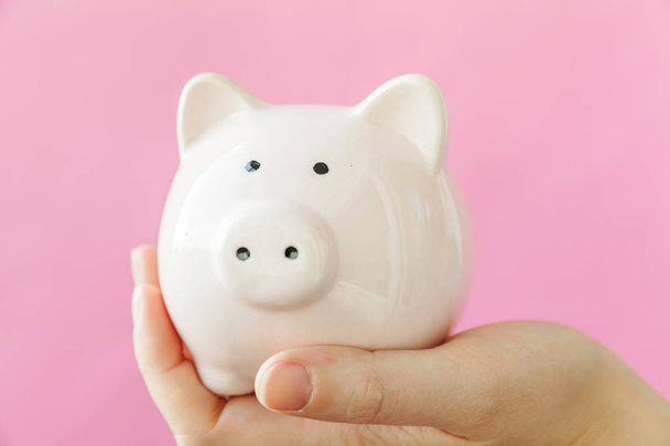 Simply design female woman hand holding pink piggy bank isolated on pink pastel colorful trendy background - Photo, Image