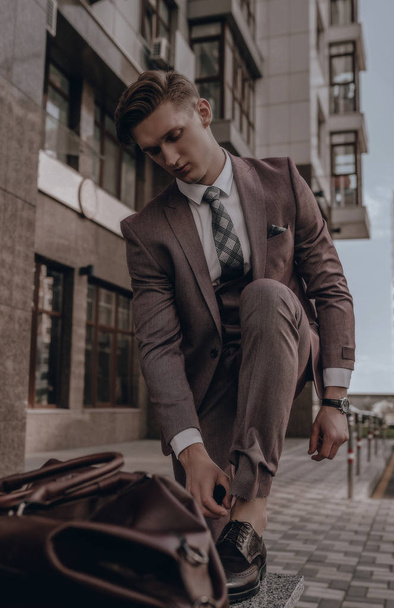 Moderne zakenman. Zelfverzekerde jongeman in vol pak in stadsgezicht op de achtergrond - Foto, afbeelding
