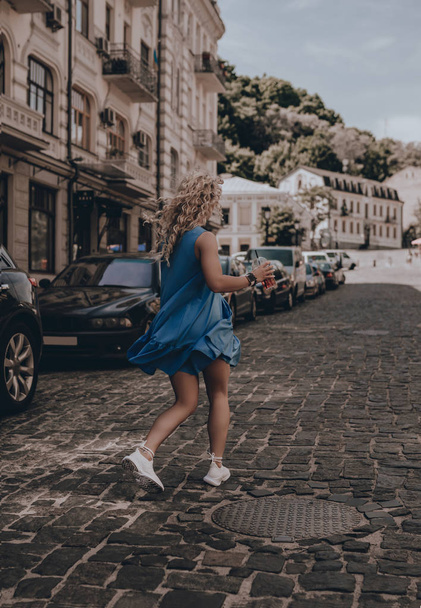 Woman walking on city street. Fashion girl in sundress summer. Young beautiful model. Portrait. Lifestyle. Jump - Fotó, kép