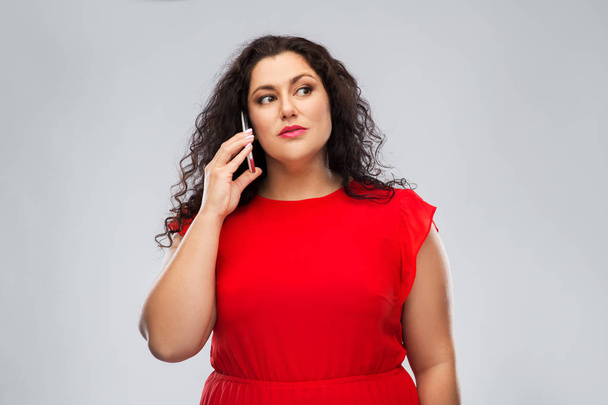 woman in red dress calling on smartphone - Foto, Bild