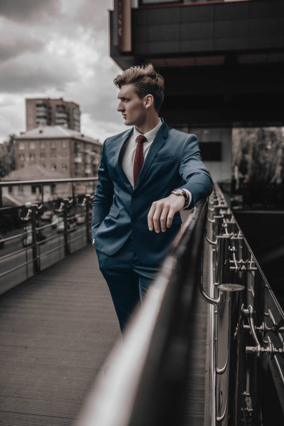 Portrait of handsome fashion businessman model dressed in elegant suit posing on street background. City urban style. Success lifestyle - Foto, imagen