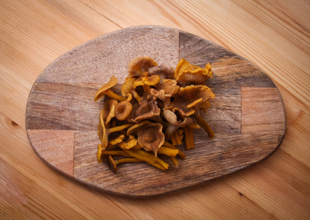 Tubular mushrooms chanterelles lying on a wooden board - Photo, Image