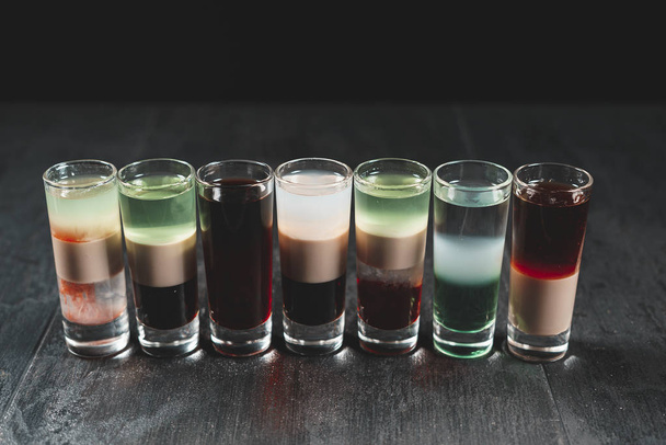 Kis poharak isznak alkoholt egy fa fekete asztalon  - Fotó, kép
