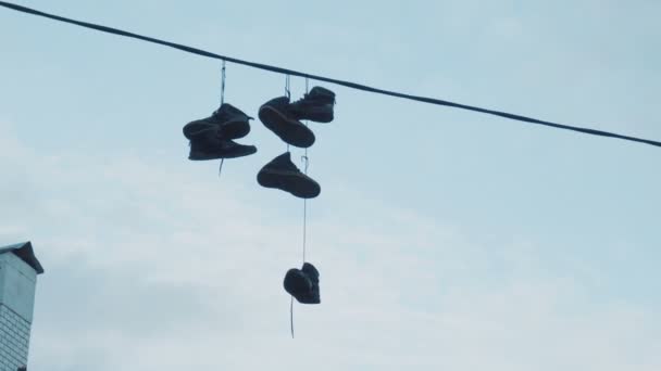 Tres pares de zapatillas colgando de cables eléctricos a una altura de nueve metros en la calle de la ciudad - Imágenes, Vídeo
