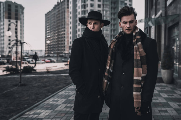 Two young stylish men posing on city street. Classic urban style. Street man model tests. - Photo, Image