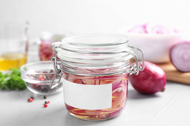 Jar of pickled onions with blank label on light table - Foto, afbeelding