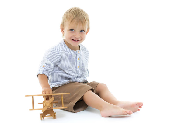 Little boy playing with wooden plane - Foto, afbeelding