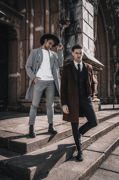 Twee mode mannen op stedelijke achtergrond in stijlvolle casual en klassieke kleding met trendy kapsel. Knappe bebaarde man model portret op City Street - Foto, afbeelding