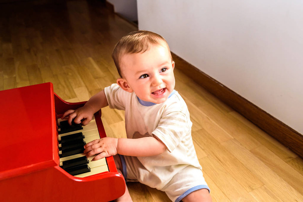 Smiling baby playing a toy piano while learning music. - Φωτογραφία, εικόνα