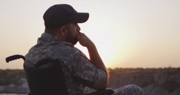 Żołnierz siedzący na wózku na łące - Materiał filmowy, wideo